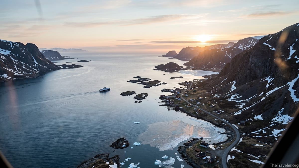 A small Arctic village and ferry under the midnight sun in a Norwegian fjord.