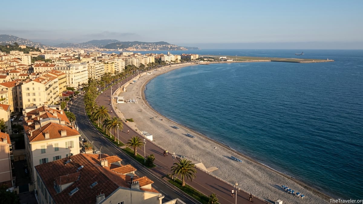 Wide view of Baie des Anges with Nice seafront, pebble beach and azure Mediterranean at sunset.