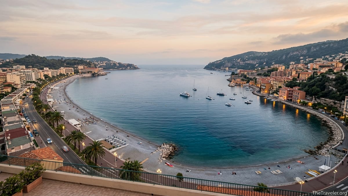 Evening view of Baie des Anges and Villefranche Bay with city lights and calm Mediterranean sea.