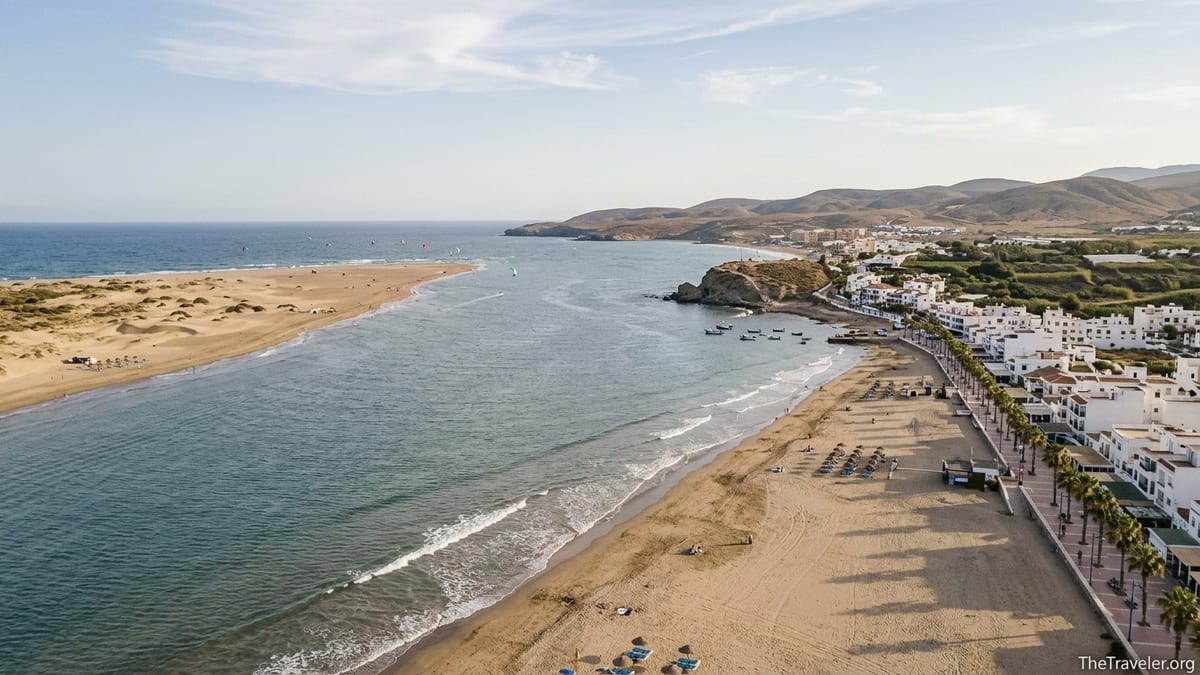 Aerial view of southern Spain coast with wide sandy beach, dunes and whitewashed seaside town.
