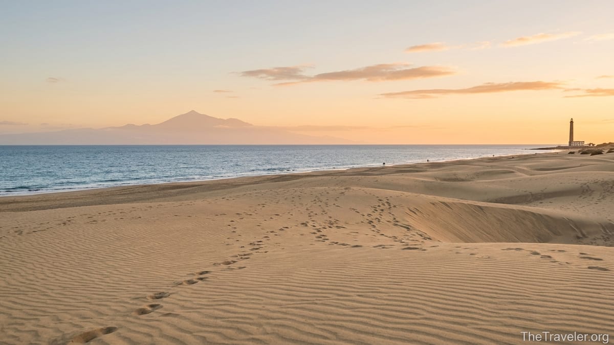 Golden sand dunes of Maspalomas at sunset with sea and distant Tenerife on the horizon.