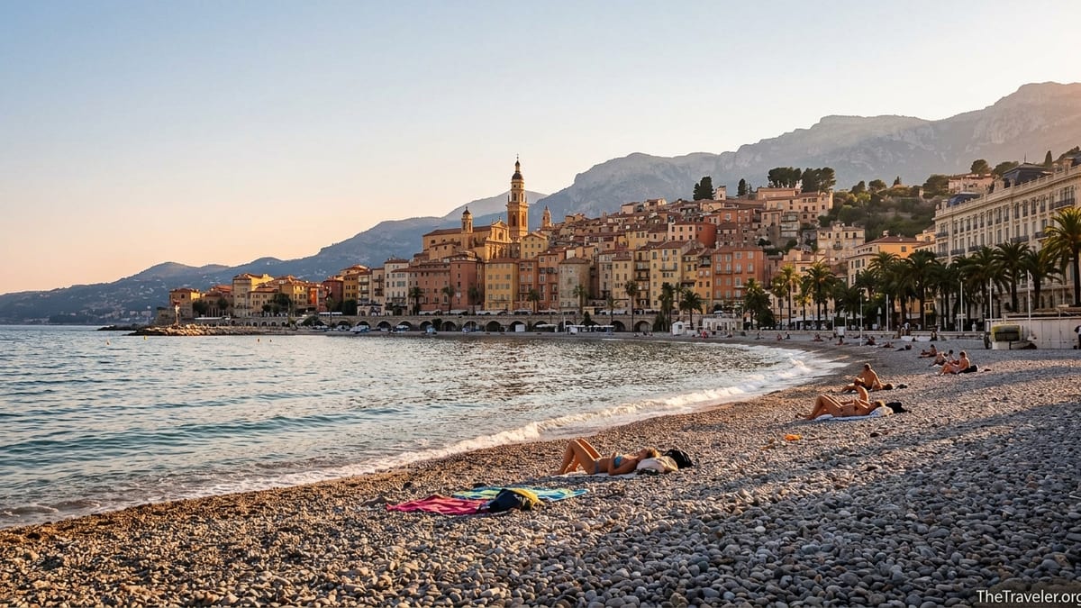 Golden hour view of Menton old town and basilica above Plage des Sablettes on the French Riviera.