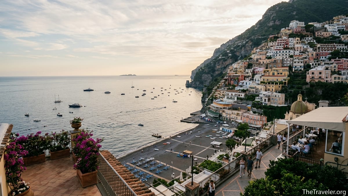 Terraced view over Positano in late spring light with calm sea and relaxed beach crowds.