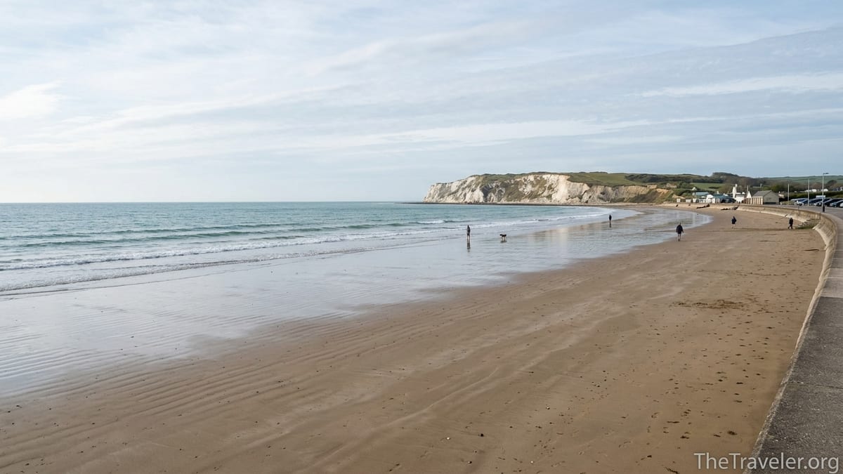Wide view of a quiet Yaverland Beach at low tide with distant walkers and Culver Down cliffs.