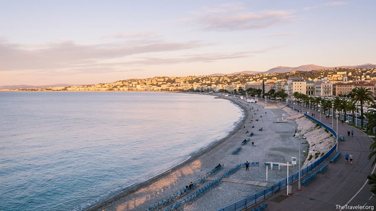 Sunrise light over Baie des Anges with quiet promenade and calm Mediterranean water near Nice.