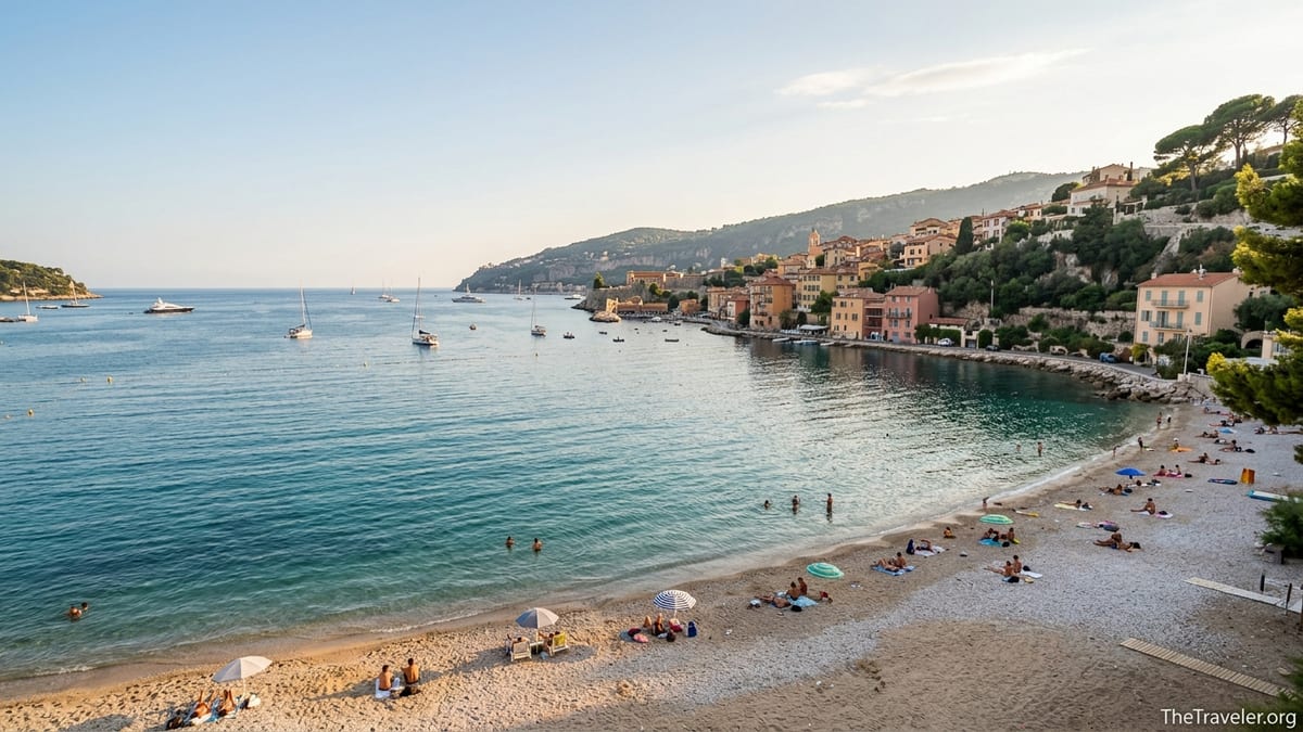 Overhead view of a lightly crowded Plage des Marinières and Villefranche-sur-Mer bay in soft golden afternoon light.