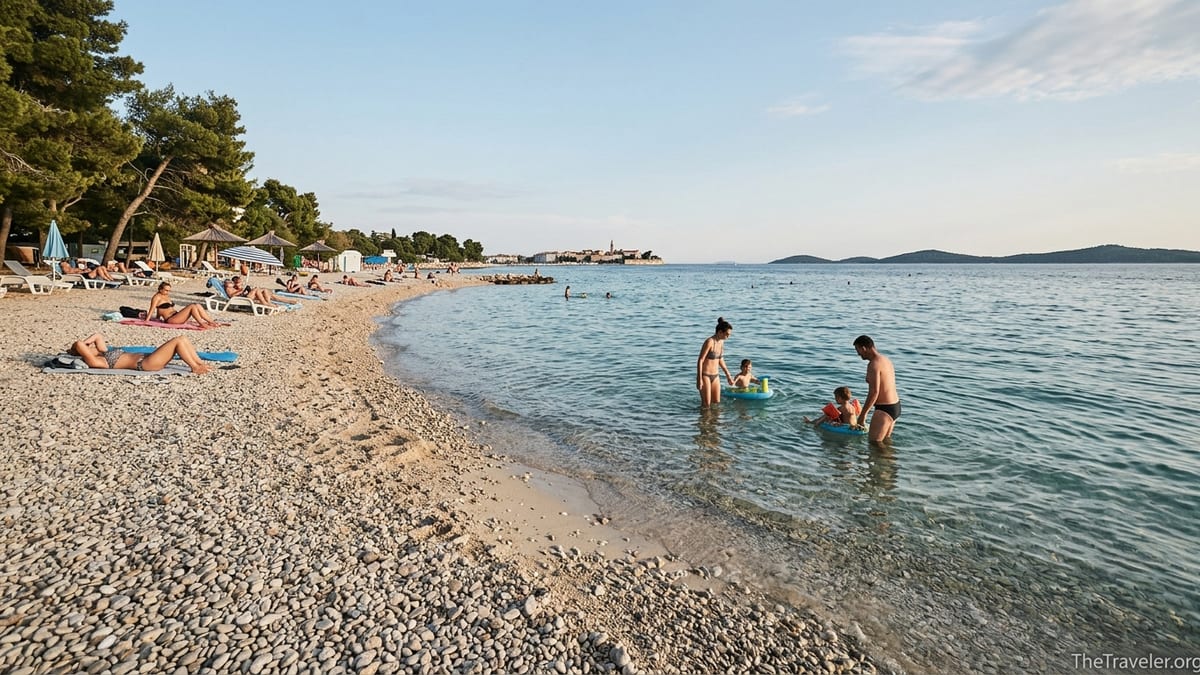 Family paddling in shallow water on a Zadar beach with pine trees and islands in the distance.