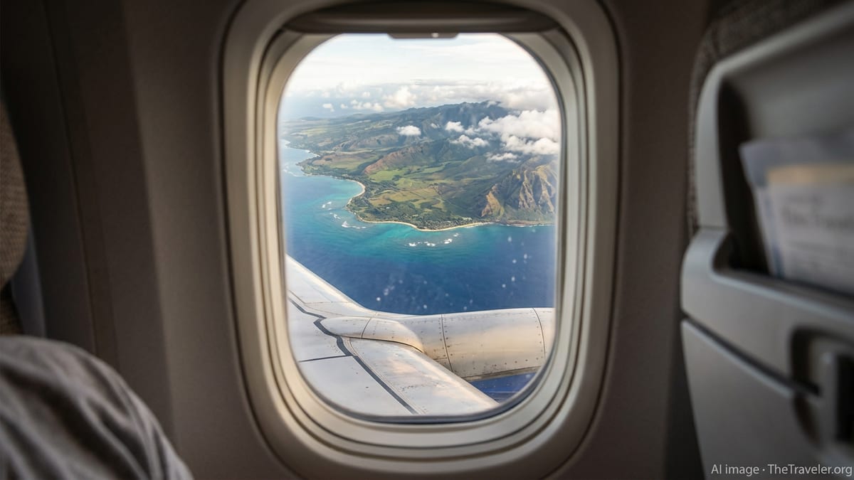 Airplane wing view approaching a Hawaiian island with blue ocean and green coastline.