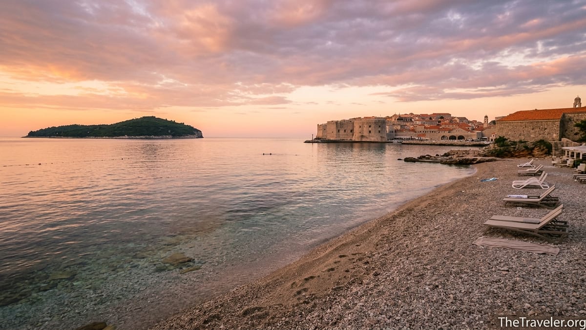 Sunrise over Dubrovnik Old Town seen from Banje Beach with calm Adriatic water.