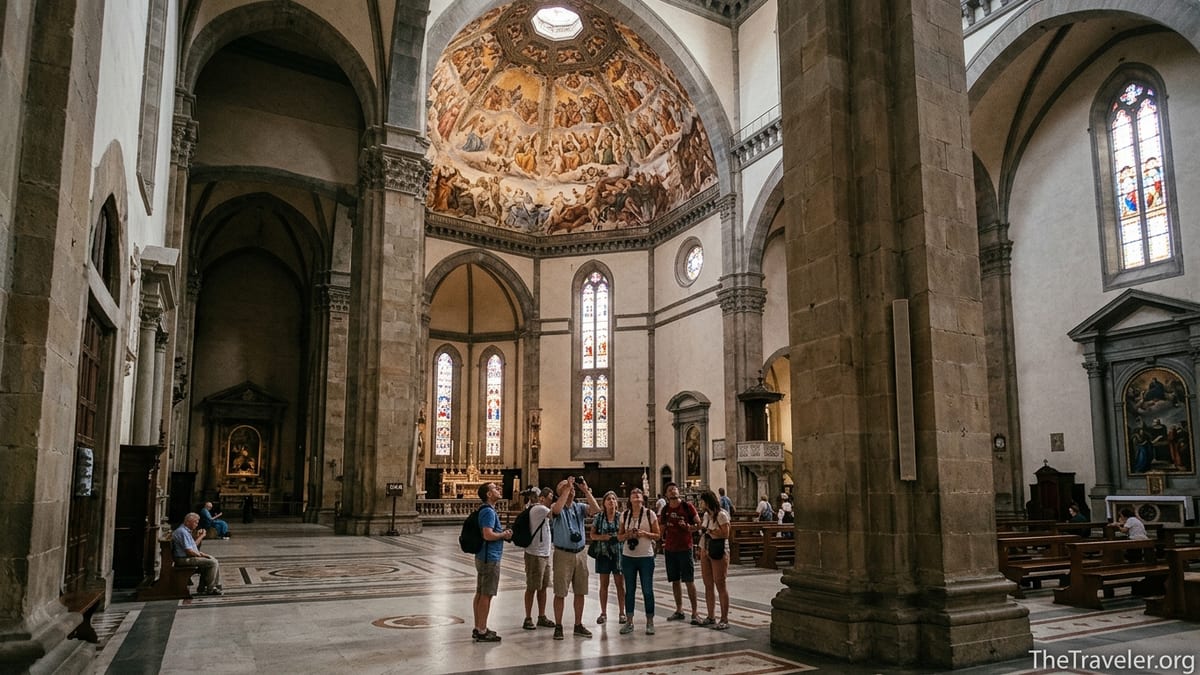 Interior of Florence’s Duomo with visitors standing beneath Brunelleschi’s frescoed dome.