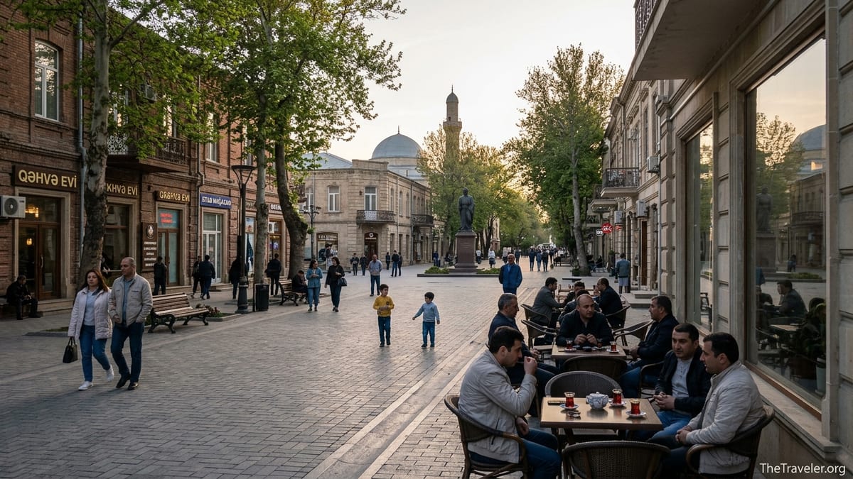 Pedestrian boulevard in Ganja, Azerbaijan, at sunset with locals walking and cafés lining the tree-lined street.