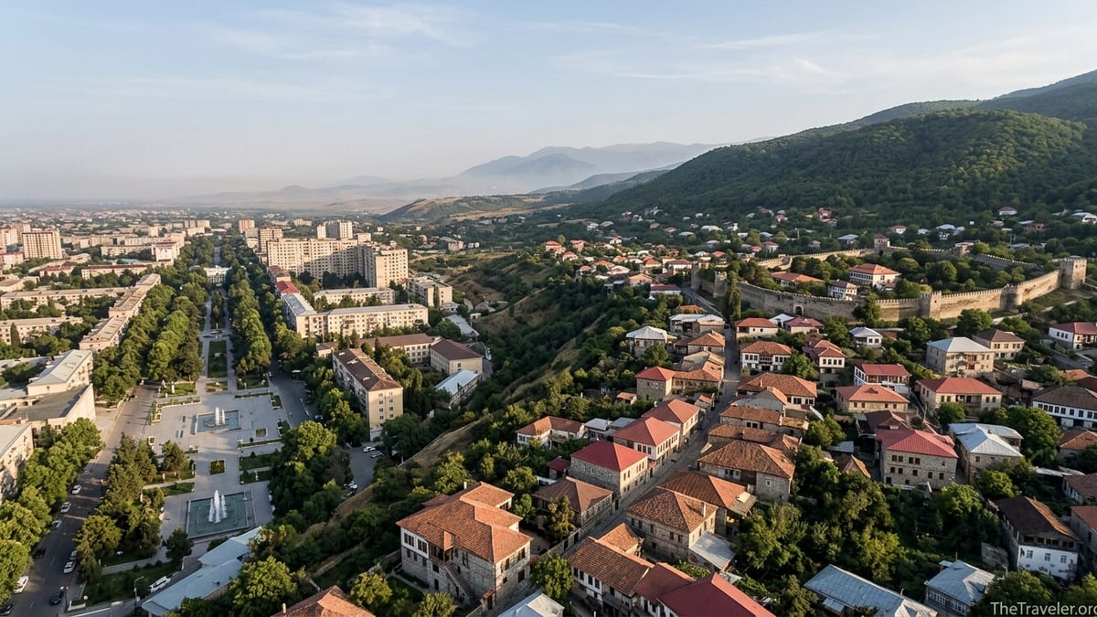 Panoramic view of Ganja and Sheki, Azerbaijan, contrasting a modern cityscape with a historic hillside town and mountain back
