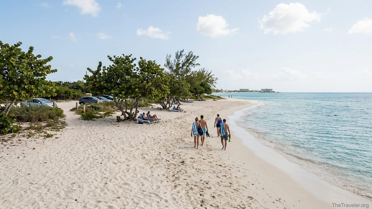 View of Seven Mile Beach on Grand Cayman with people walking from a sandy access path toward turquoise water.