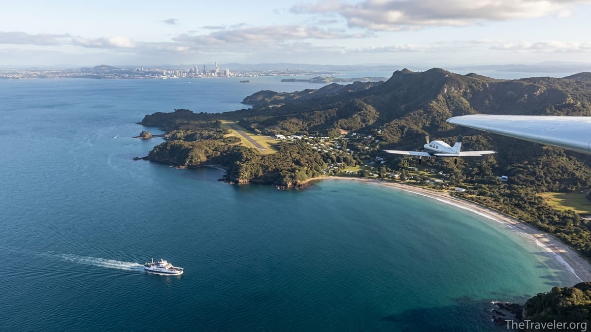 A small plane approaches Great Barrier Island as a car ferry crosses the Hauraki Gulf below.