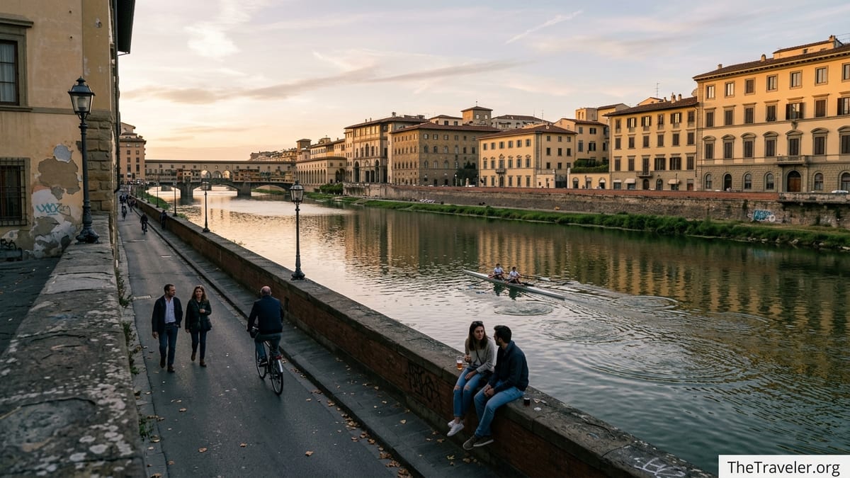 Quiet stretch of the Arno River in Florence with locals walking and a rowing boat passing at sunset.