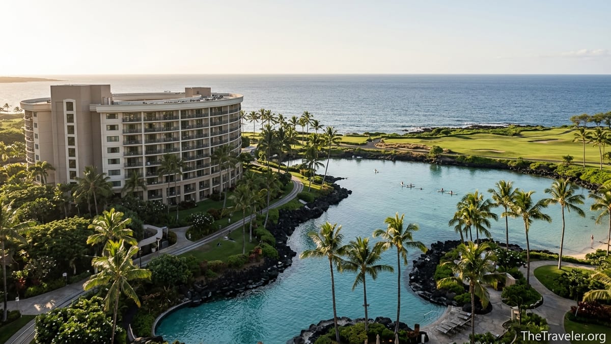 Oceanfront view of Hilton Grand Vacations Club Ocean Tower Waikoloa with lagoon, pools and palm trees at sunset.