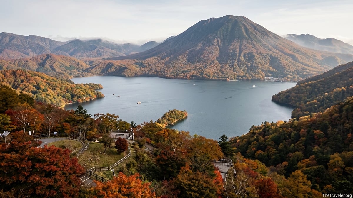 Autumn forest around Lake Chuzenji in Nikko with red and gold trees and distant mountain.