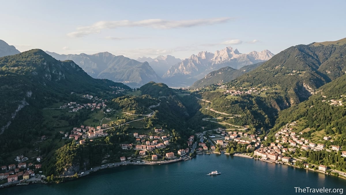 Aerial view of Lake Como villages leading toward the distant Dolomites at sunset.
