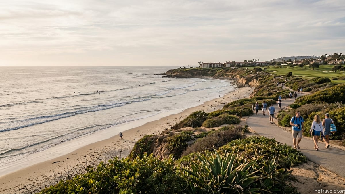 Golden hour view of Carlsbad coastline with beach, bluffs, and resort in the distance.
