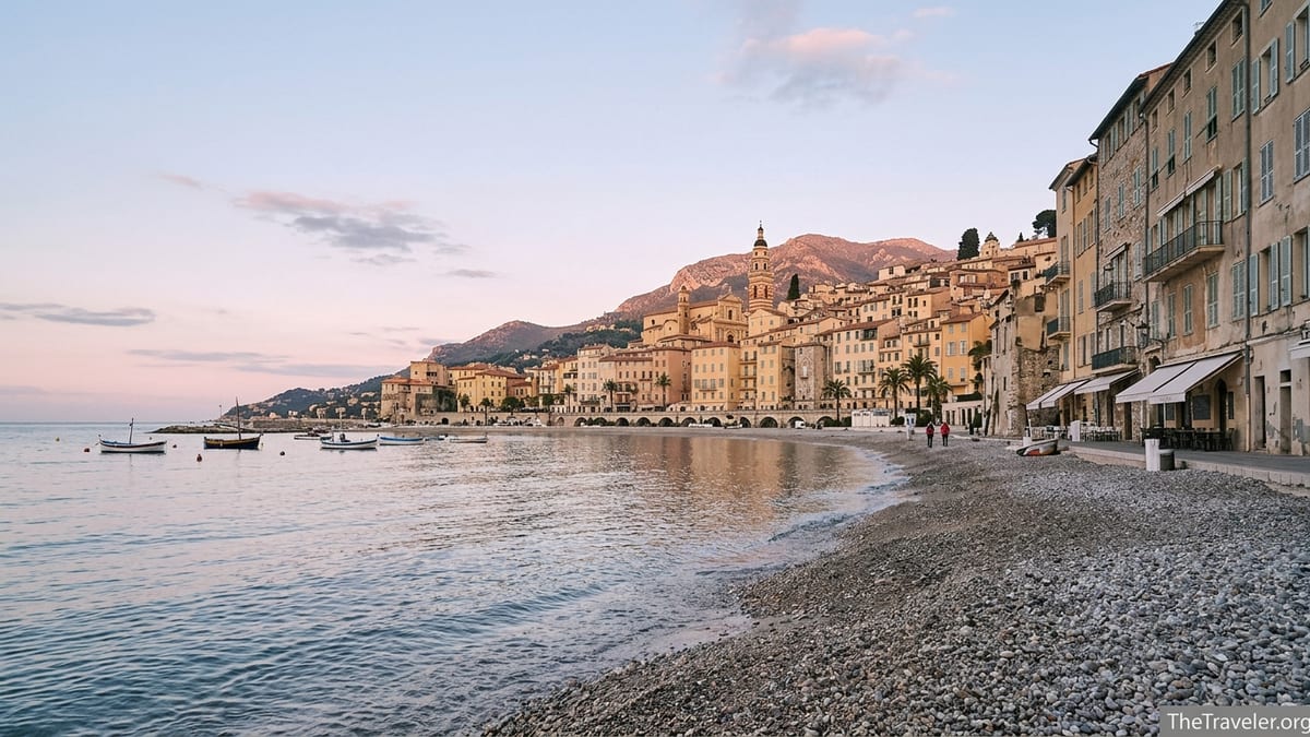 Sunrise over Menton’s pastel old town seen from the beach at Plage des Sablettes.
