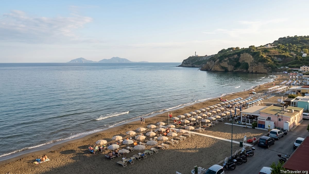 Late afternoon view of Miseno beach near Naples with umbrellas, calm sea and Capo Miseno headland.