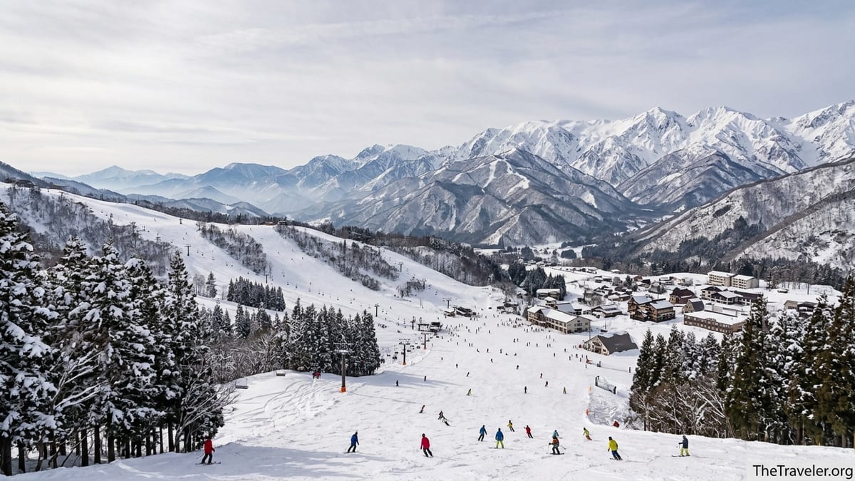 Snowy ski slopes above a Japanese alpine village in Hakuba Valley with mountains in the background.