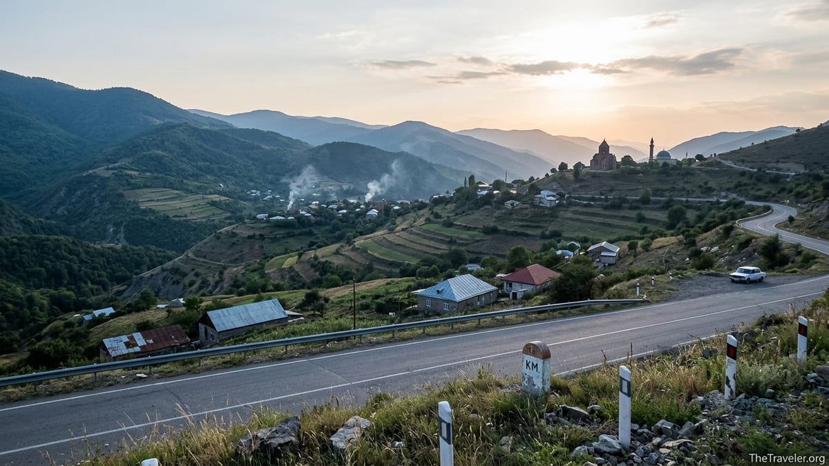Mountain road overlooking the rugged, forested hills and villages of the Nagorno Karabakh region at dusk.