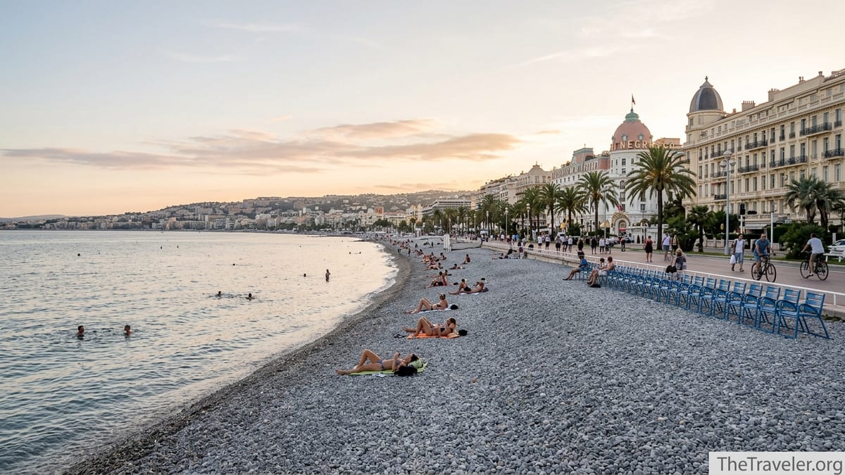 Golden hour view of Nice’s Promenade des Anglais with pebbled beach, blue chairs and Belle Époque seafront buildings.