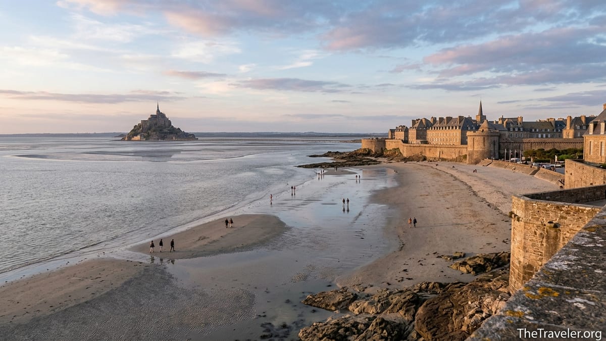 Golden hour view of Saint-Malo ramparts and tidal bay looking toward distant Mont-Saint-Michel.