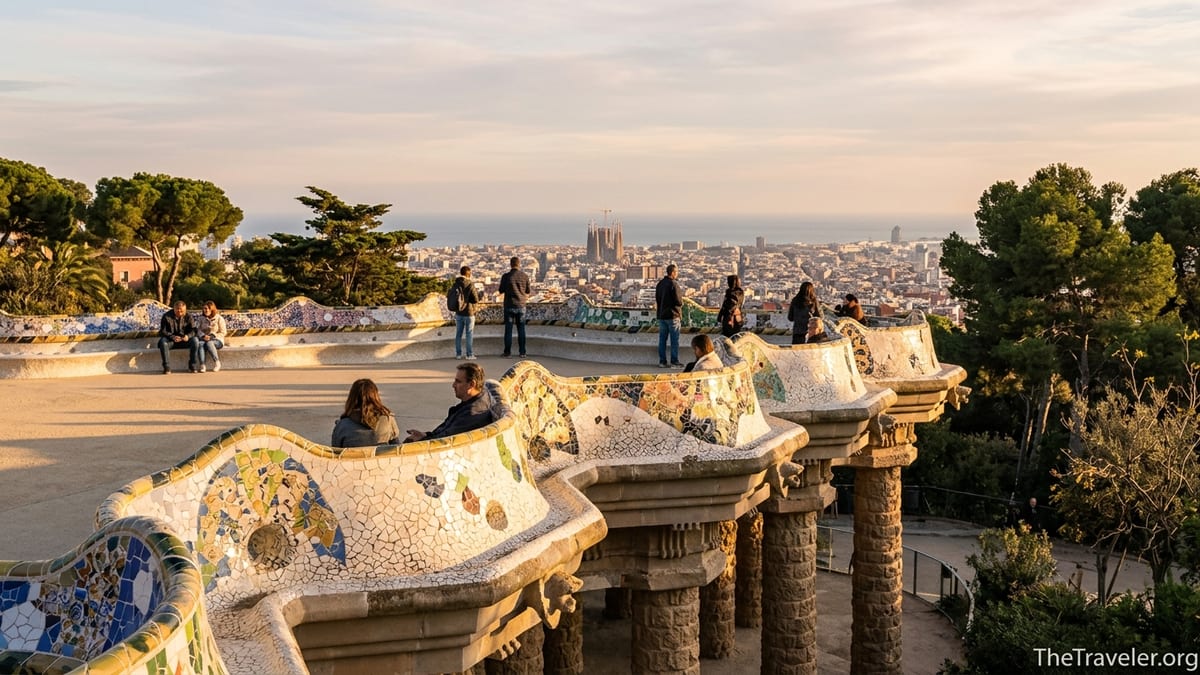 Visitors on the mosaic terrace of Park Güell in Barcelona at golden hour with city views.