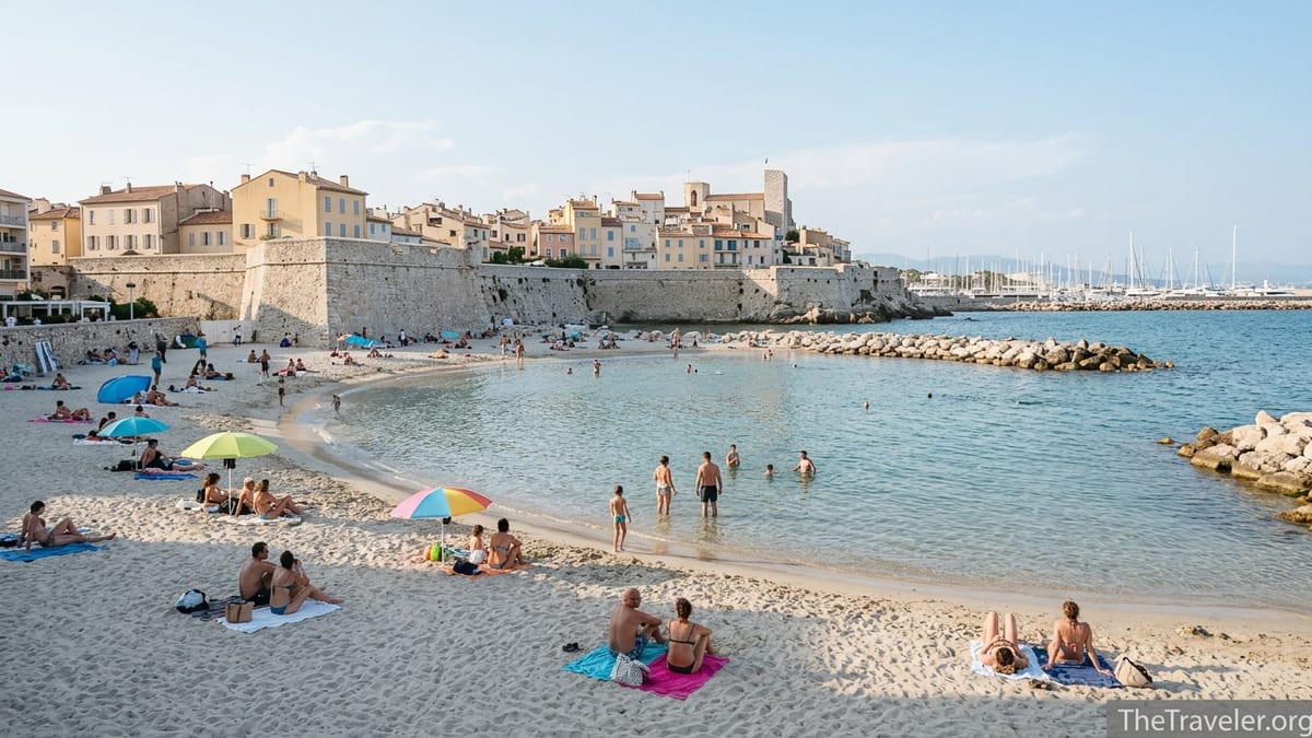 Sandy cove of Plage de la Gravette beneath Antibes’ old town ramparts on a calm sunny afternoon.