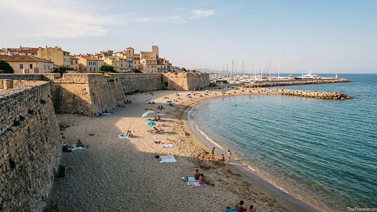 View from Antibes ramparts over Plage de la Gravette cove, sand, sea, and old town.