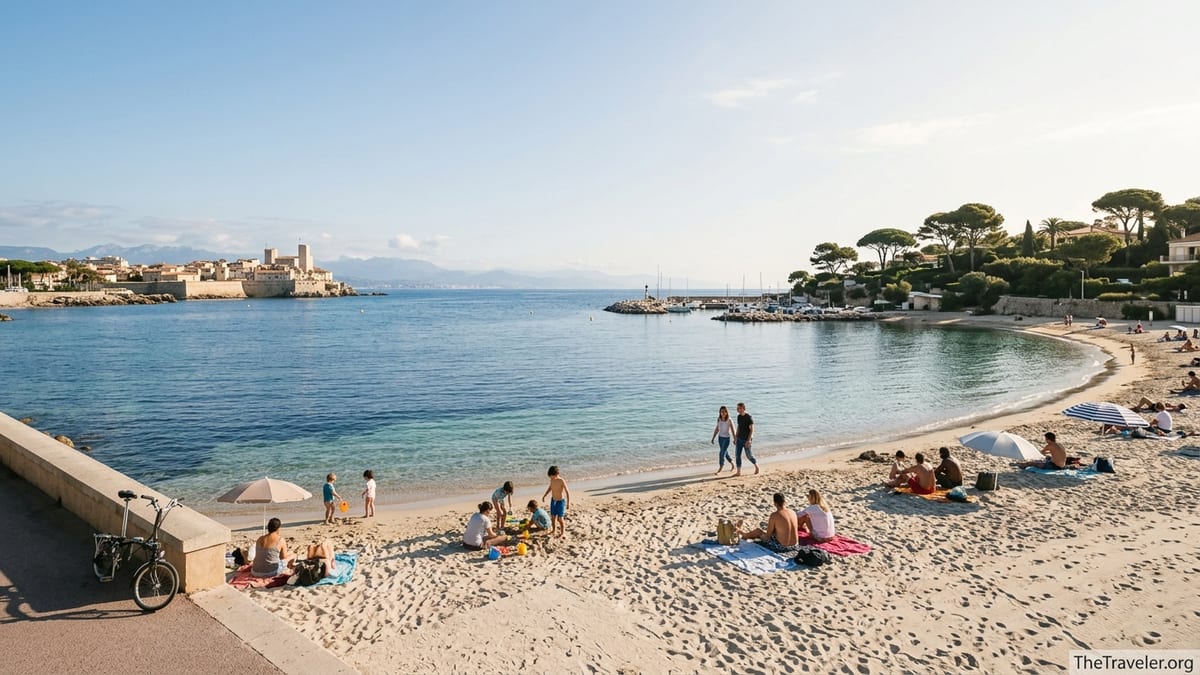 Wide view of Plage de la Salis in Antibes with bathers on soft sand and Cap d’Antibes in the background.