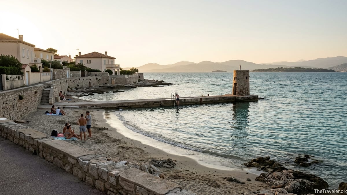 Late afternoon view of Plage des Ondes with jetty, calm turquoise water and distant Esterel hills.