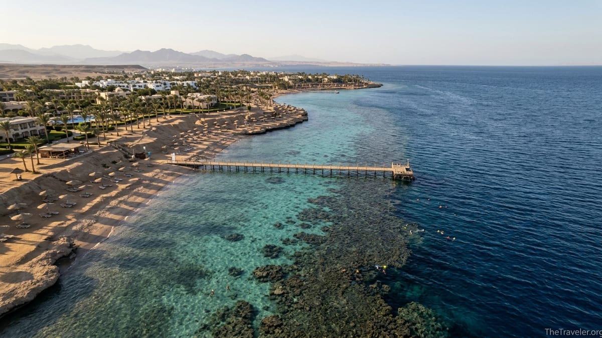 A Red Sea resort bay in Egypt with jetty, coral reef and snorkelers seen from above at sunset.