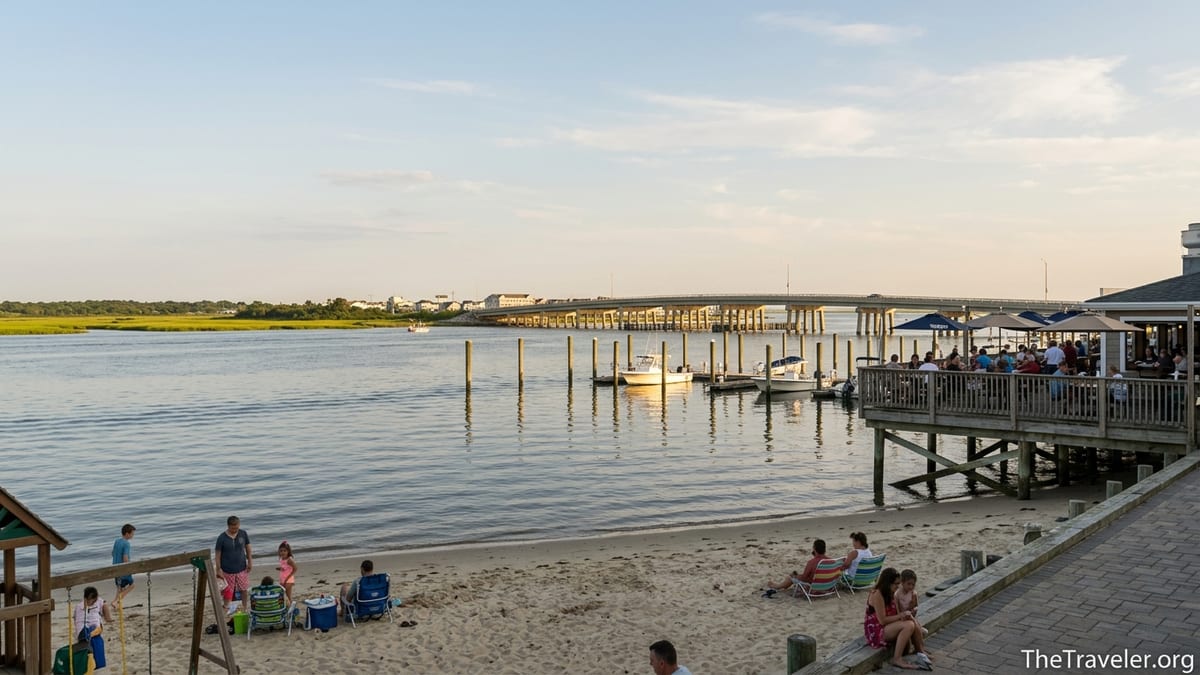 Bayside beach and waterfront deck in Somers Point with bridge and boats at sunset.