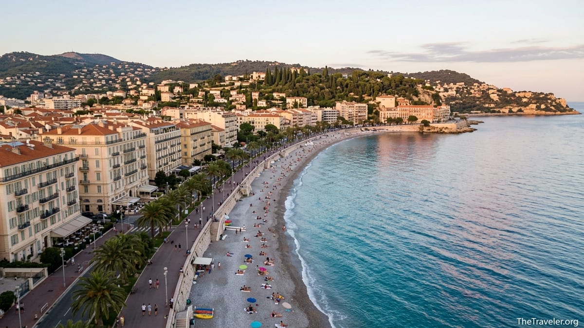 Aerial view of a Mediterranean bay in the South of France with beach, promenade and pastel buildings at sunset.