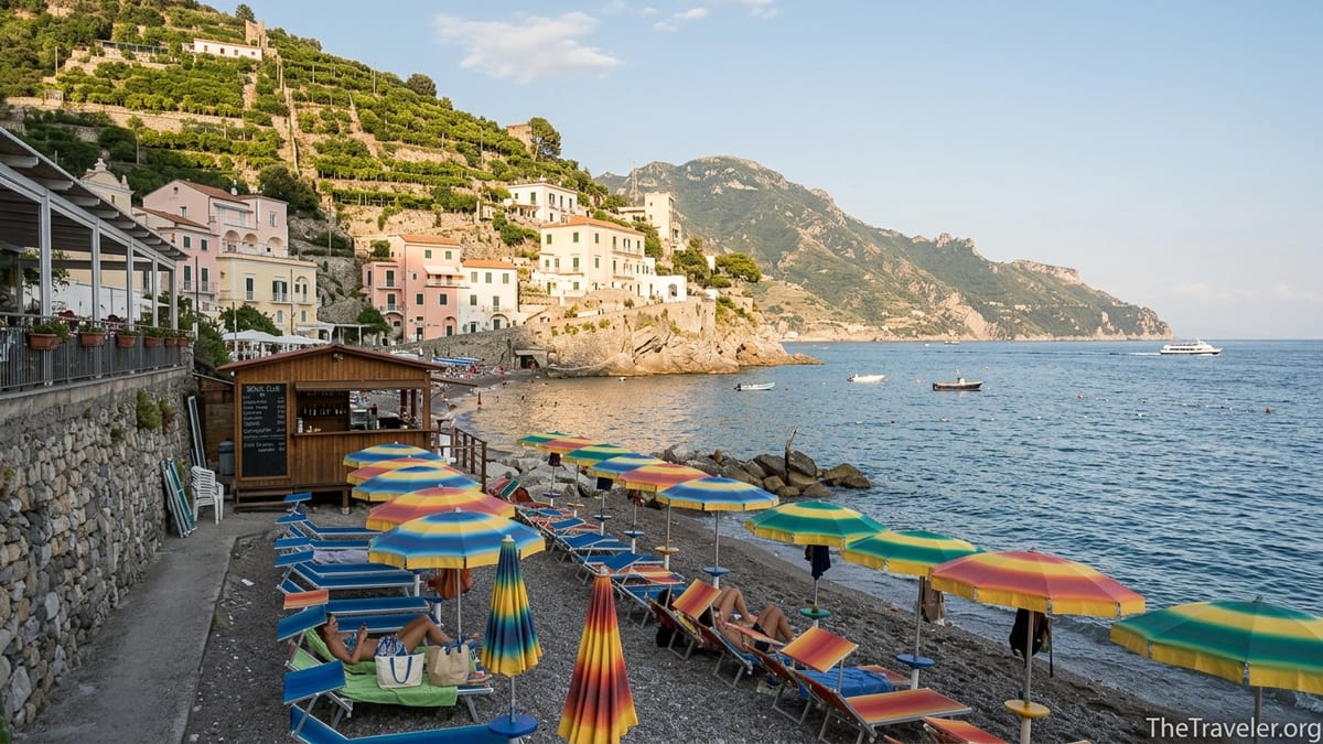 Southern Italy beach with umbrellas, hillside houses and calm blue sea at golden hour.
