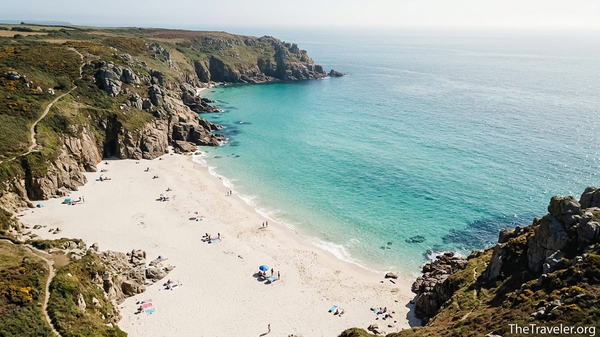 Aerial view of a white sand Cornish cove with turquoise water and steep cliffs.