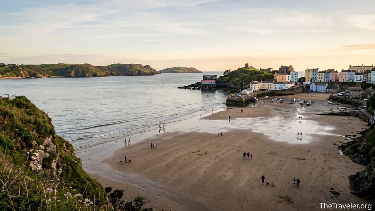 Tenby’s pastel houses overlooking a wide sandy Welsh beach at low tide in soft evening light.